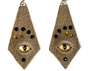 4007 Pendientes de piel color tostado con ojos de dragón dorados y pedrería dorada y negra.