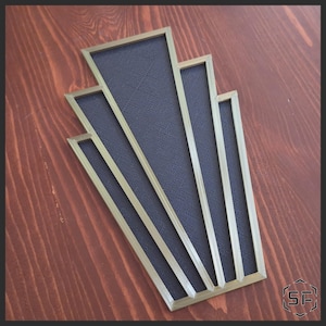 May include: Art Deco wall decoration with a fan-shaped design. It has a dark blue textured centre framed by gold-coloured borders. The design is set against a dark wood background.