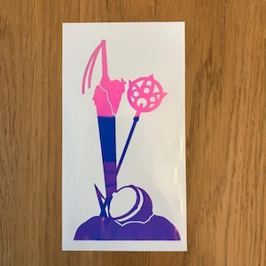 May include: A white sticker featuring a stylized design in shades of pink, blue, and purple. The design includes a staff, a hooded figure, and a circular emblem. The sticker is likely for decorative purposes.