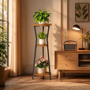 May include: A three-tier plant stand featuring a black metal frame and circular wooden shelves. The top shelf holds a green leafy plant in a white pot, the middle shelf holds a small green plant in a white pot, and the bottom shelf holds pink flowers.