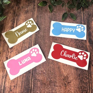 May include: Four bone-shaped stickers in gold, blue, pink, and red, each with a white paw print and text. The gold sticker says "Name", the blue says "HAPPY", the pink says "LUNA", and the red says "Charlie".