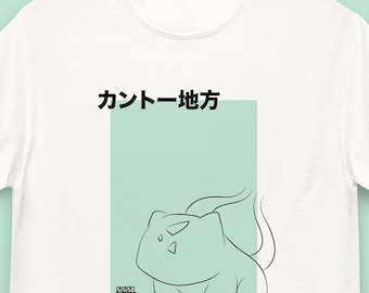 May include: White t-shirt featuring a line drawing of a Bulbasaur character within a light green rectangle. Japanese text is above the graphic. The shirt is hanging on a black hanger.