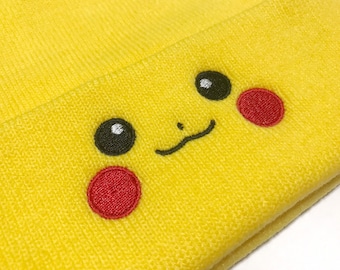 May include: Yellow knit beanie featuring an embroidered Pikachu face. The design includes black eyes, a black mouth, and red cheek circles. The hat is made of a soft, textured material, perfect for fans of the popular character.