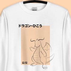 May include: White sweatshirt with a dragon illustration and Japanese text. The design includes a peach-colored rectangle with the number "0149" at the bottom. The dragon is outlined in black, and the Japanese text reads "ドラゴン・ひこう".