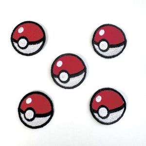 May include: Five embroidered patches in the shape of a Poké Ball. Each patch features a red upper half, a white lower half, and a white circle in the center. The patches are outlined in black.