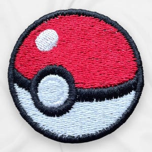 May include: Embroidered patch featuring a red and white Pokeball design. The patch has a black border and a white circle on the top left. The bottom half is white, and the top half is red.