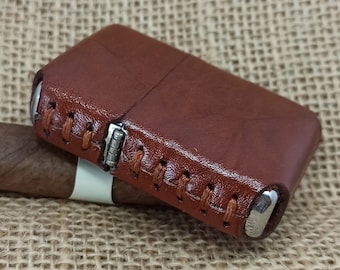 May include: A brown leather lighter case with stitching around the edges. The case is closed and has a silver metal hinge.