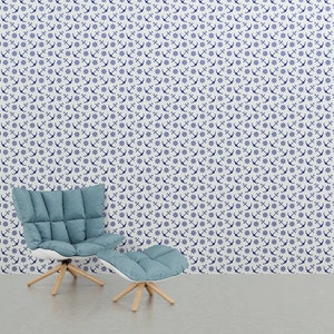 Puede incluir: Un interior de tem&aacute;tica n&aacute;utica con un sill&oacute;n azul y una otomana frente a una pared cubierta con un patr&oacute;n de anclas y timones blancos y azul marino. La silla y la otomana tienen patas de madera clara.