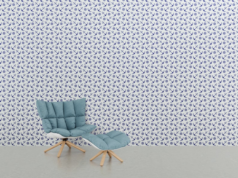 Puede incluir: Un interior de tem&aacute;tica n&aacute;utica con un sill&oacute;n azul y una otomana frente a una pared cubierta con un patr&oacute;n de anclas y timones blancos y azul marino. La silla y la otomana tienen patas de madera clara.