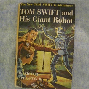 May include: A vintage book cover featuring a boy and a giant robot. The book title is "Tom Swift and His Giant Robot" by Victor Appleton II. The cover art is illustrated in a retro style with bright colors.