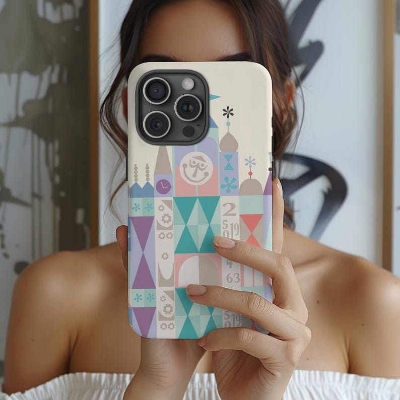 Puede incluir: Una funda blanca para iPhone con un dise&ntilde;o geom&eacute;trico colorido que presenta un castillo y los n&uacute;meros 2, 5, 1, 9, 6, 3. La funda tiene un fondo blanco con un patr&oacute;n geom&eacute;trico de color rosa pastel, azul, verde y morado.