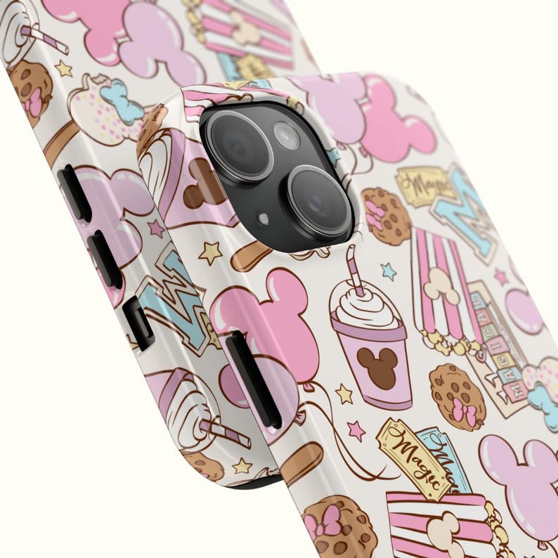May include: A smartphone case featuring a repeating pattern of pink mouse-shaped balloons, chocolate chip cookies, striped popcorn containers, and drinks with straws. The design includes tickets with the word Magic printed in cursive script.
