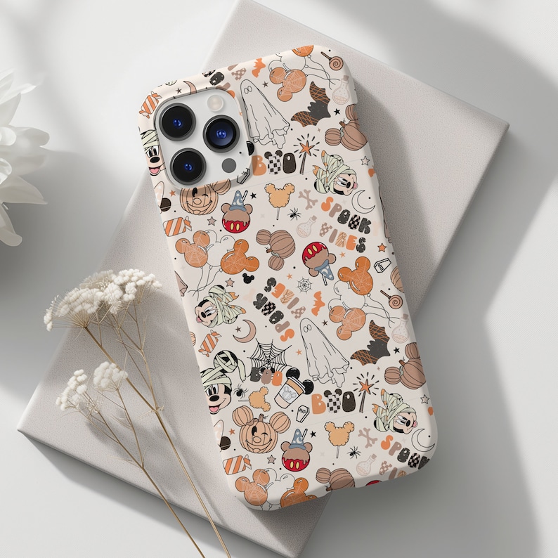 May include: A white phone case featuring a repeating pattern of Halloween-themed cartoon characters, pumpkins, ghosts, and the words "Spook Vibes" in orange and black. The case has a glossy finish and a camera cutout.
