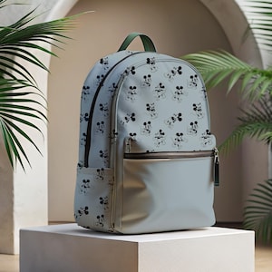 Peut inclure: Un sac à dos bleu clair avec un imprimé Mickey Mouse noir et blanc. Le sac à dos a un tirette de fermeture éclair verte et une fermeture éclair marron.