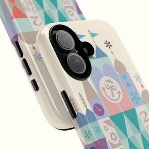 Puede incluir: Una funda de tel&eacute;fono blanca con un dise&ntilde;o geom&eacute;trico colorido que presenta un castillo de dibujos animados y el texto "25 Years of Magic".