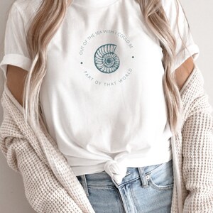 May include: White t-shirt with a blue seashell graphic and the text "Out of the sea wish I could be part of that world".