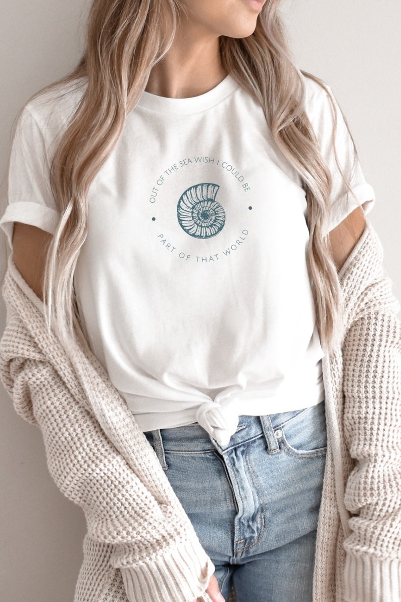 May include: White t-shirt with a blue seashell graphic and the text "Out of the sea wish I could be part of that world".