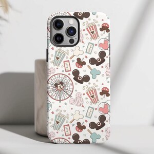 May include: A white smartphone case featuring a repeating pattern of amusement park icons including popcorn buckets, ferris wheels, balloons, tickets, and mouse-ear shaped treats in shades of brown, pink, and light blue on a white background.