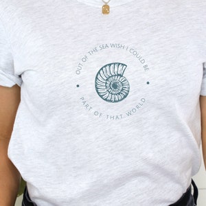 May include: A heather grey t-shirt with a graphic of a seashell and the text "Out of the sea wish I could be part of that world."