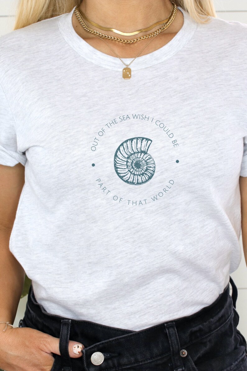 May include: A heather grey t-shirt with a graphic of a seashell and the text "Out of the sea wish I could be part of that world."