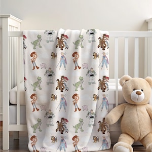 May include: A white fleece blanket with a repeating pattern of Toy Story characters, including Woody, Buzz Lightyear, Jessie, and Rex. The characters are depicted in a cartoon style and are surrounded by a white background.
