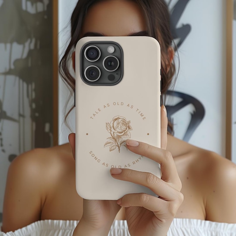 May include: A white iPhone case with a floral design and the text "Tale as old as time, song as old as rhyme".