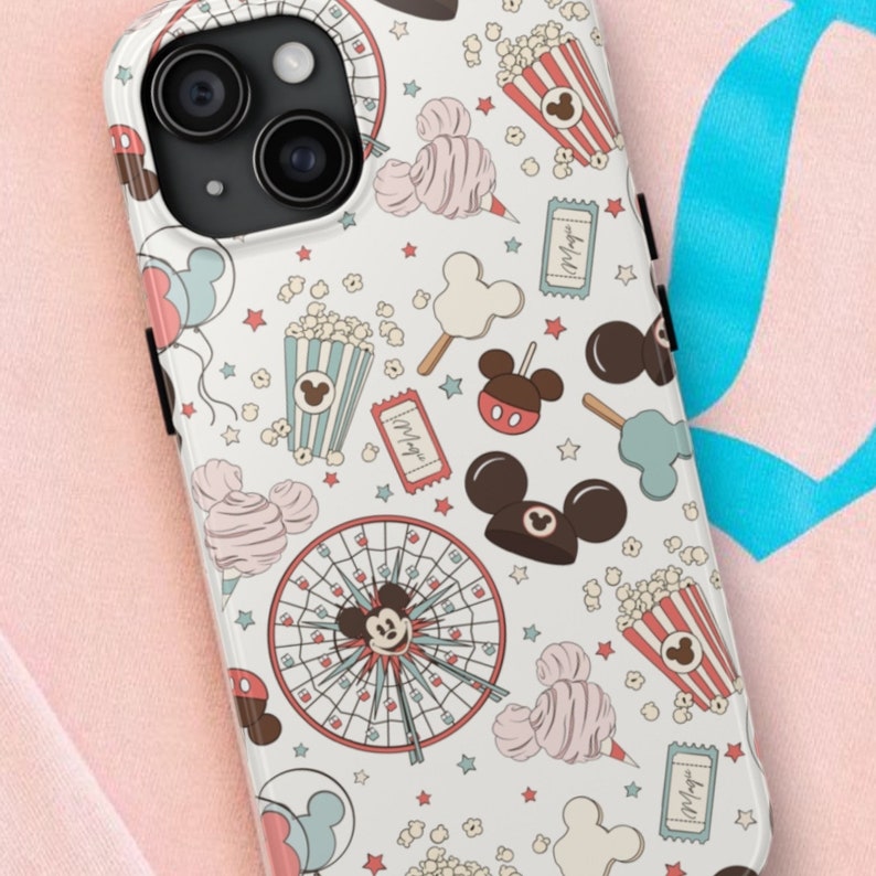 May include: A white phone case featuring a repeating pattern of amusement park icons including ferris wheels, popcorn buckets, cotton candy, tickets, and mouse-ear shaped treats in muted red, blue, and brown tones with small stars scattered throughout.
