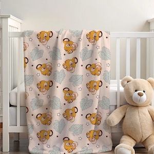 May include: A soft, plush blanket featuring a repeating pattern of Simba's face from The Lion King. The pattern also includes blue tropical leaves and white stars on a light beige background.