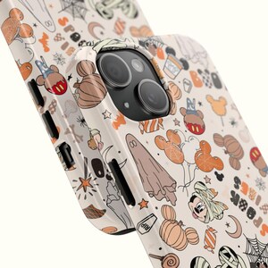 May include: A phone case with a Halloween design. The case has a cream background with orange, black, and white illustrations of Mickey Mouse pumpkins, ghosts, and spiderwebs. The word "SPOOK" is visible on the side.