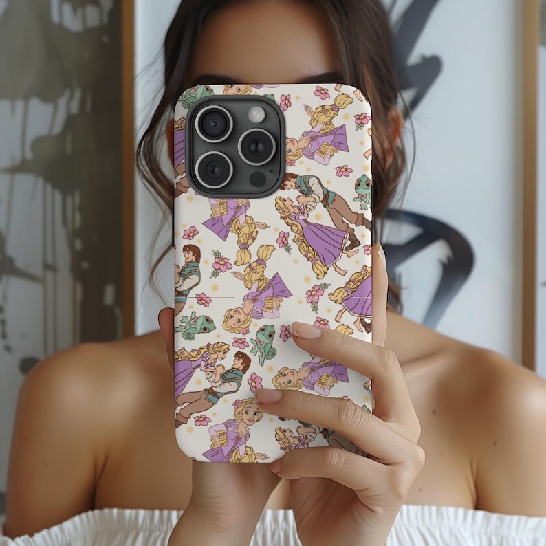 May include: A white phone case with a repeating pattern of Rapunzel and Flynn Rider from the Disney movie Tangled. The characters are illustrated in a cartoon style and are surrounded by flowers and a green chameleon.