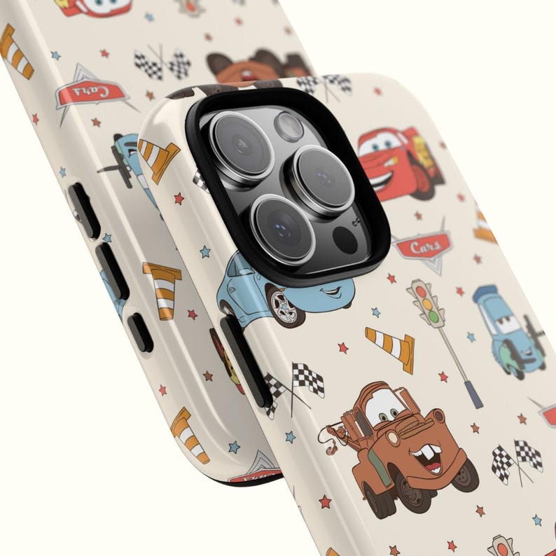 May include: A cream-colored phone case featuring a repeating pattern of characters from the movie Cars, including a brown tow truck, a red race car, and a blue car, along with traffic cones, checkered flags, and the Cars logo.