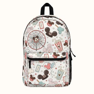 May include: White backpack with a colorful pattern of Mickey Mouse, popcorn, balloons, and other carnival-themed imagery.