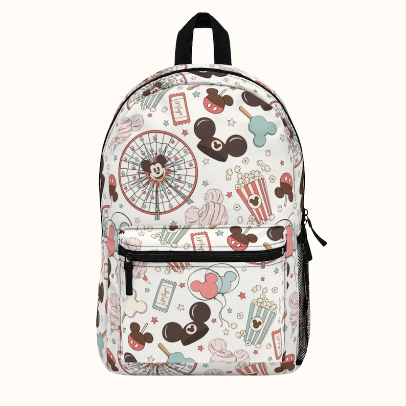 May include: White backpack with a colorful pattern of Mickey Mouse, popcorn, balloons, and other carnival-themed imagery.