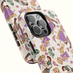 May include: A white phone case with a pattern of Rapunzel and Flynn Rider from the Disney movie Tangled. The case has a black camera bump with three lenses.