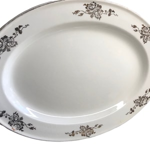 May include: White oval serving platter with a silver floral design around the edge.