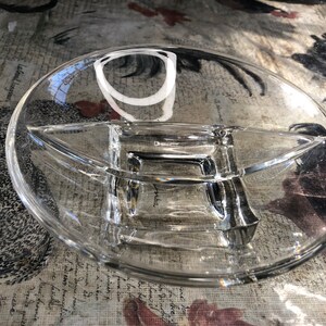 Puede incluir: Un plato de servir de vidrio transparente con tres secciones divididas. El plato es redondo y tiene una sección central elevada.