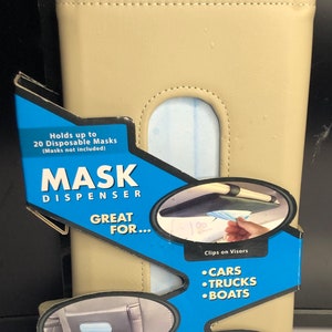 May include: A beige leather mask dispenser with a blue and black label that says "Mask Dispenser" and "Great For..." with a list of places to use the dispenser, including cars, trucks, boats, home, work, and school. The dispenser holds up to 20 disposable masks.
