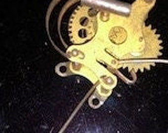 May include: A close-up of a vintage brass clock mechanism with visible gears, levers, and a curved spring. The mechanism is set against a dark, possibly black, background. The brass components show signs of age and wear.