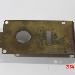 Brass plate 1 3/4" x 3 1/4 with four mounting holes and a roller bearing at one end.
