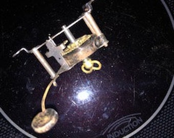May include: A close-up of a small, antique clock mechanism with a brass winding key and a black metal base.