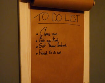 May include: A wooden wall-mounted to-do list holder with a brown paper roll. The paper is labeled "TO DO LIST" and has handwritten tasks: "Clean oven", "Pick up Rids", "Get Know husband", and "Finish To do list".