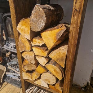 Peut inclure: Un support de stockage de bois de chauffage en bois rempli de bûches coupées. Le support est en bois teinté et de forme rectangulaire. Les bûches sont de tailles et de formes variées, avec le grain et l'écorce du bois visibles.