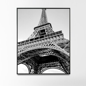以下が含まれることがあります： フランスのパリにあるエッフェル塔の白黒写真。写真は低い角度から撮影されており、塔を見上げています。塔の複雑な金属構造が見えます。
