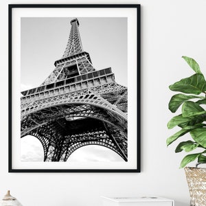 以下が含まれることがあります： フランスのパリにあるエッフェル塔の白黒写真。写真は低い角度から撮影されており、塔を見上げています。