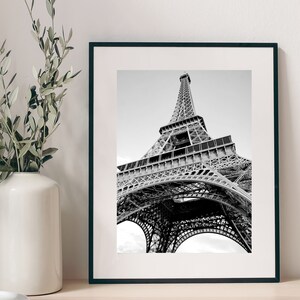 以下が含まれることがあります： フランスのパリにあるエッフェル塔の白黒写真。写真は低い角度から撮影されており、塔を見上げています。