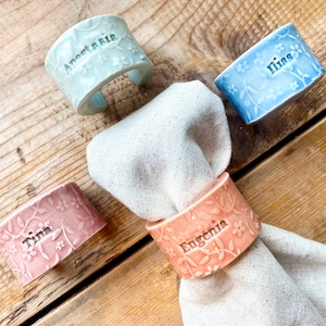 May include: Four ceramic napkin rings with floral designs and personalized names: "Anastasia", "Ilina", "Tina", and "Eugenia".