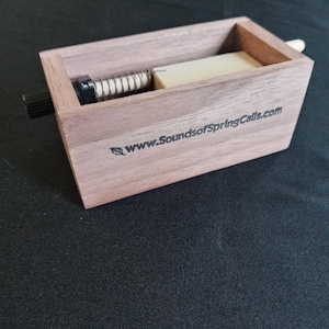 May include: A wooden box with a spring mechanism inside. The box is labeled with the website "www.SoundsofSpringCalls.com".
