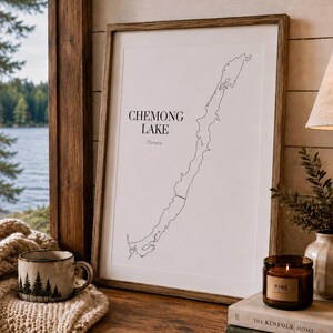 May include: A framed wall art print featuring a black line map of Chemong Lake, Ontario, on a white background. The text reads Chemong Lake and Ontario. The print is housed in a simple wooden frame, displaying a clean, minimalist aesthetic.