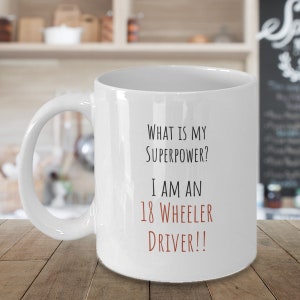 May include: White ceramic coffee mug with black text that reads "What is my superpower? I am an 18 wheeler driver!!" The text "driver!!" is in brown.