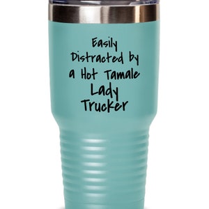 May include: A teal blue stainless steel tumbler with a silver lid. The tumbler has the text "Easily Distracted by a Hot Tamale Lady Trucker" printed on it.